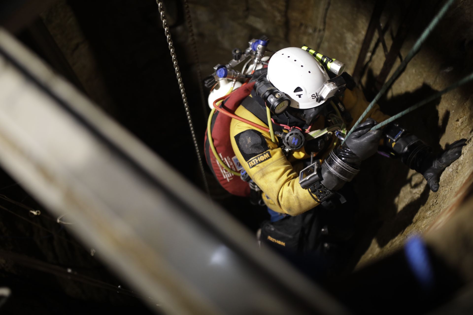a diver being lowered into a well on ropes